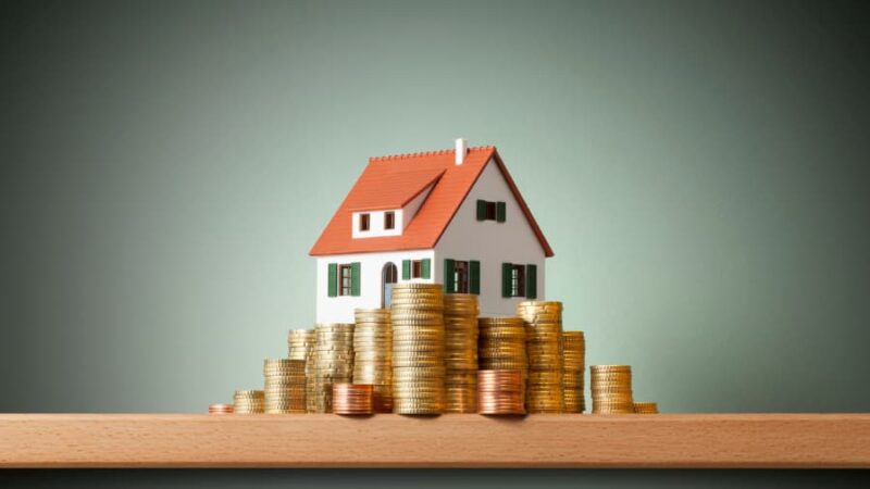 Model of house surrounded by stacked coins