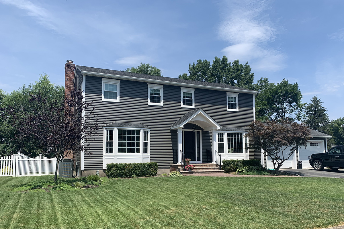 Mann Large dark grey home with a beautiful lawn.