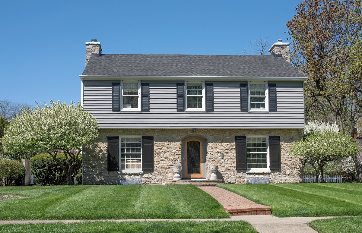 Two,Story,Home,With,Gray,Siding,And,Tan,Stone,In Grey and brick home with a beautiful front yard.