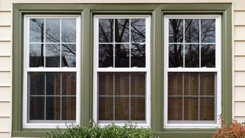 Double-hung windows with green trim on front of house