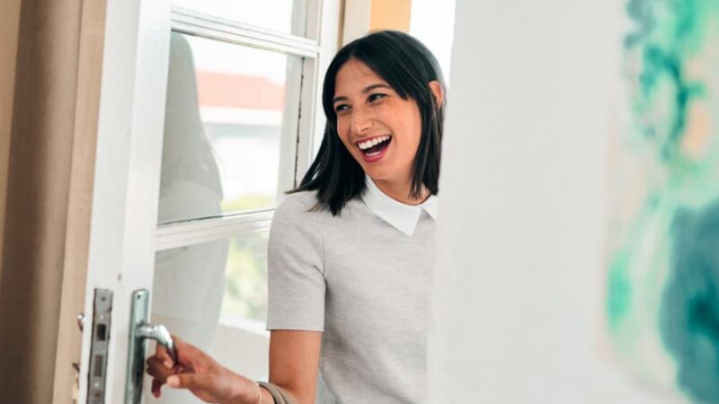 Happy woman opening the front door of home