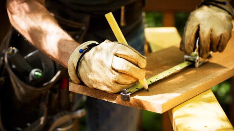 A carpenter measuring a plank for a new deck