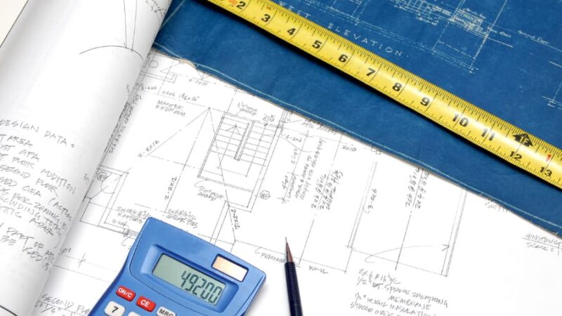 Calculator and measuring tape resting on top of blueprints
