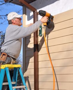 Construction worker installs new vinyl siding on house