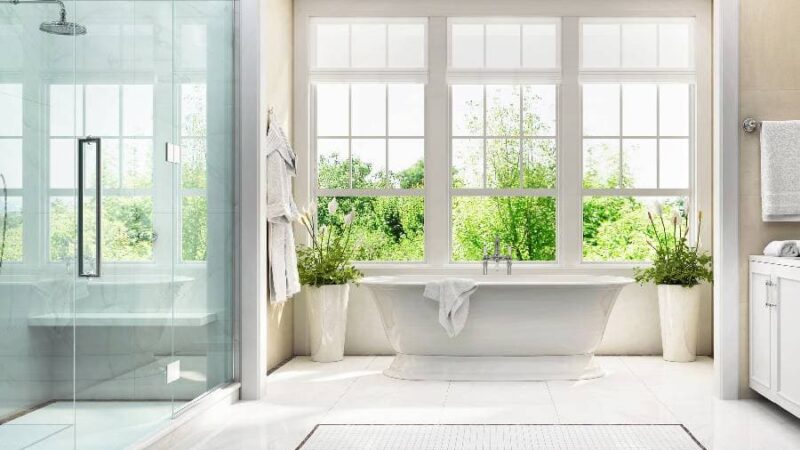 Three open windows behind white bathtub