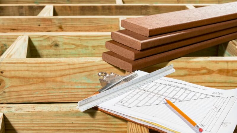 Deck plans in clipboard sitting on deck build in progress