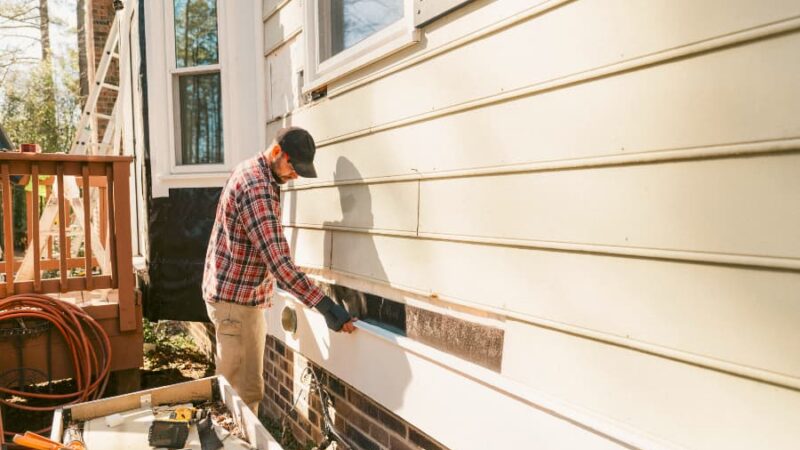 Construction worker repairing colonial style house siding