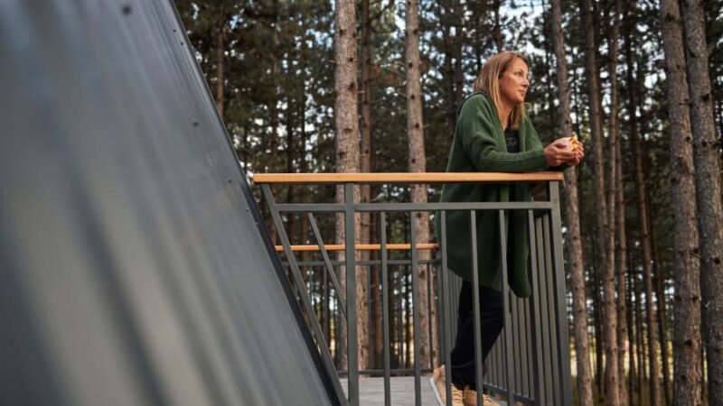 Homeowner leaning on deck railing with forest in background